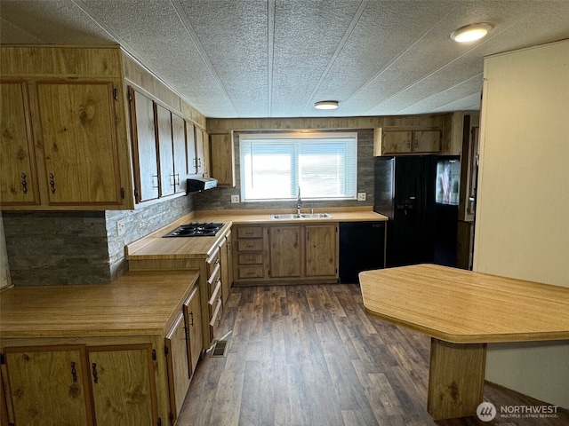 kitchen featuring a sink, light countertops, range hood, dark wood-style floors, and black appliances