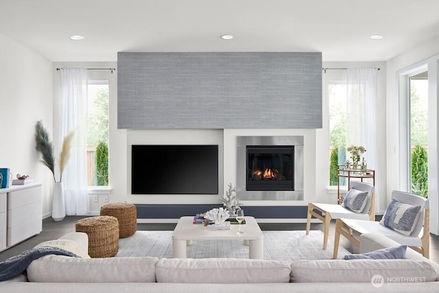 living room with a glass covered fireplace, plenty of natural light, and recessed lighting