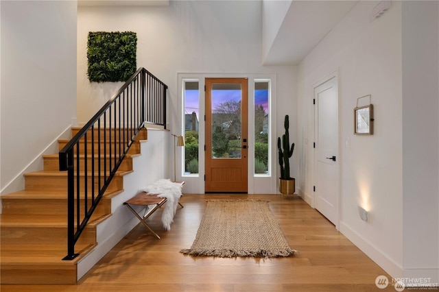 entryway with stairs, baseboards, and wood finished floors