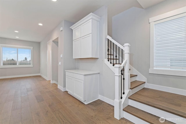 staircase featuring recessed lighting, wood finished floors, and baseboards