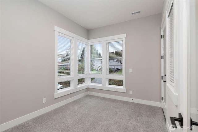 carpeted spare room featuring visible vents and baseboards