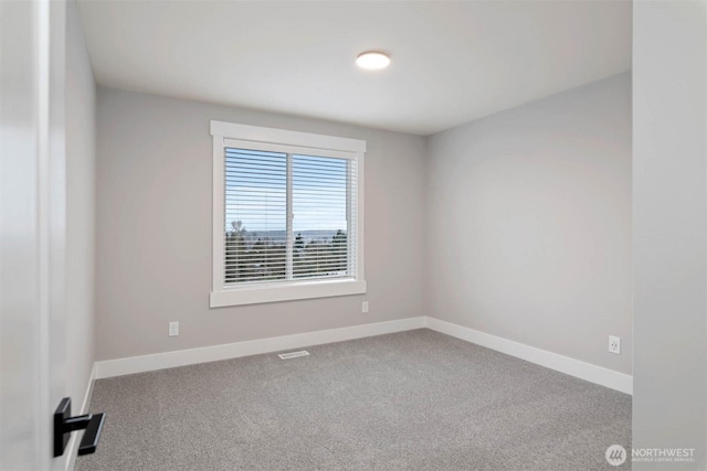 carpeted spare room featuring visible vents and baseboards