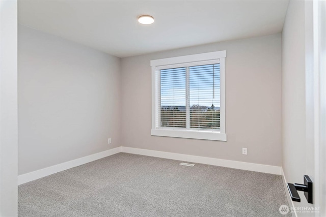 empty room with carpet, visible vents, and baseboards