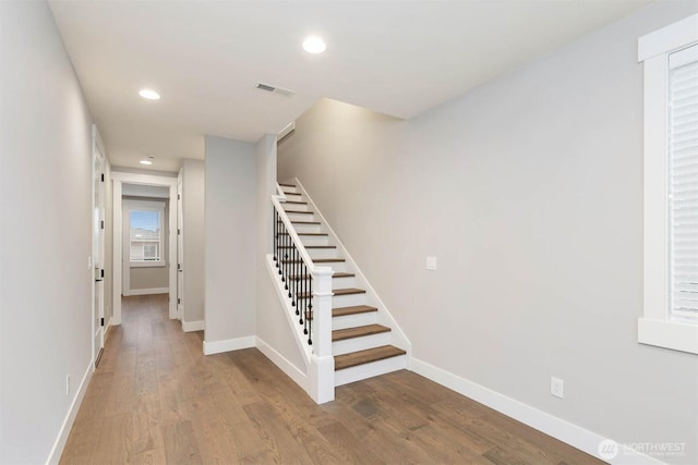 staircase featuring baseboards, visible vents, and wood finished floors