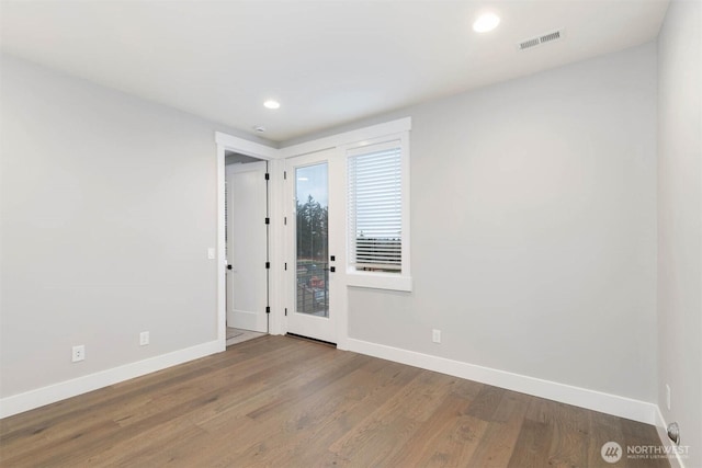 empty room with recessed lighting, wood finished floors, visible vents, and baseboards