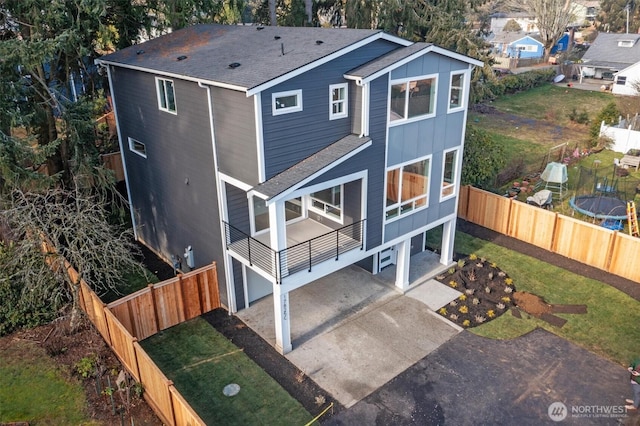 exterior space featuring board and batten siding, a front yard, roof with shingles, and fence