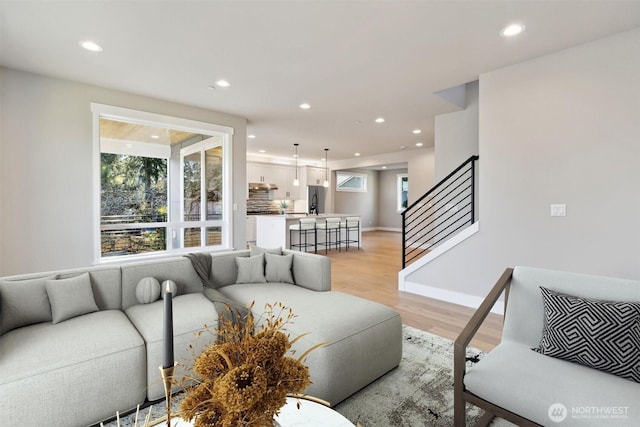 living area featuring recessed lighting, baseboards, stairway, and light wood finished floors