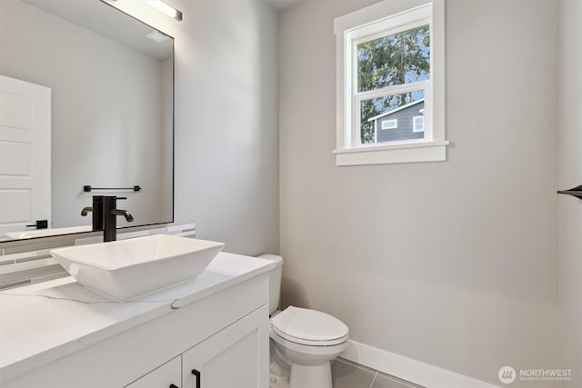 bathroom featuring tile patterned flooring, baseboards, vanity, and toilet