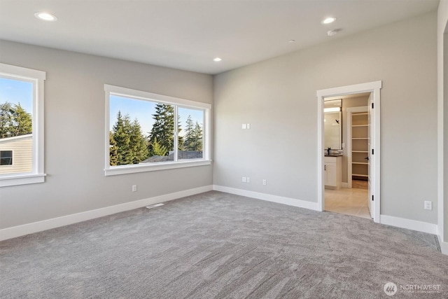 unfurnished bedroom featuring recessed lighting, carpet flooring, ensuite bath, and baseboards