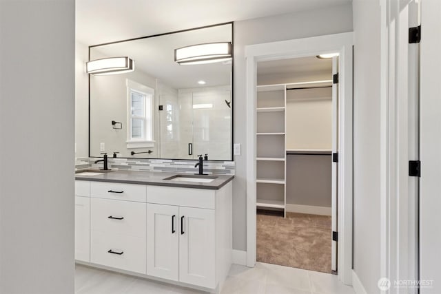 full bathroom featuring a stall shower, a walk in closet, a sink, and backsplash