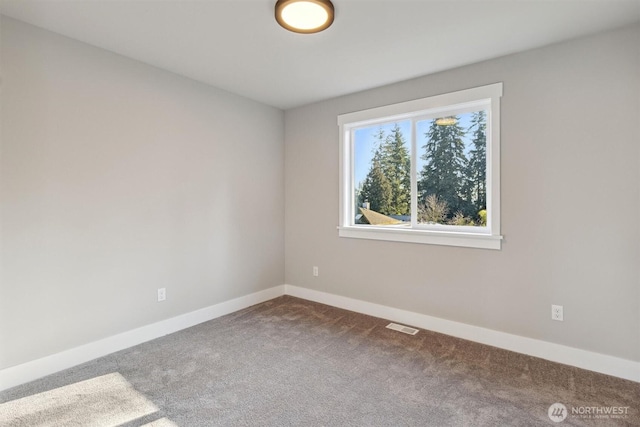 carpeted spare room with visible vents and baseboards