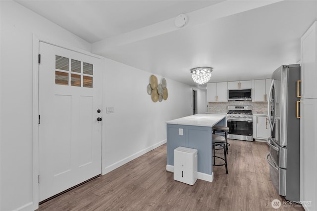 kitchen featuring a kitchen island, white cabinetry, stainless steel appliances, and wood finished floors