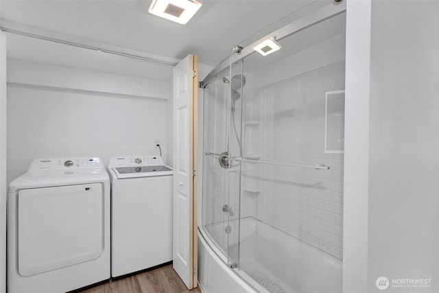 clothes washing area featuring laundry area, wood finished floors, and washing machine and clothes dryer