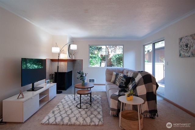 living room with crown molding, visible vents, a tiled fireplace, a textured ceiling, and baseboards