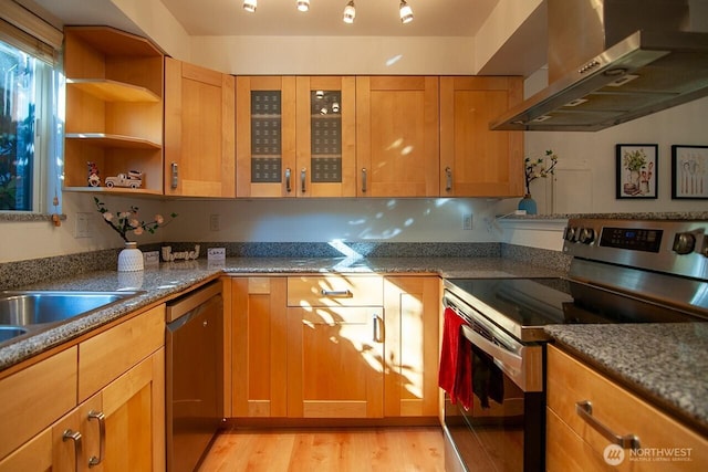 kitchen with stone counters, mail area, appliances with stainless steel finishes, light wood-style floors, and wall chimney range hood