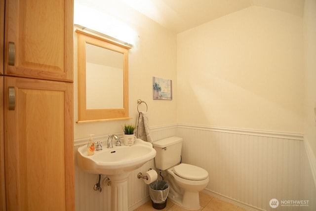 bathroom featuring vaulted ceiling, wainscoting, tile patterned flooring, and toilet