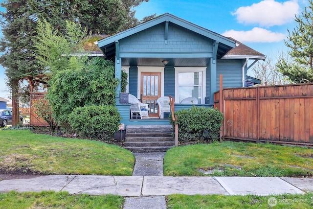 bungalow-style home with a porch, a front yard, and fence