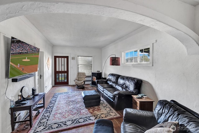 living room featuring wood finished floors, ornamental molding, and a textured wall