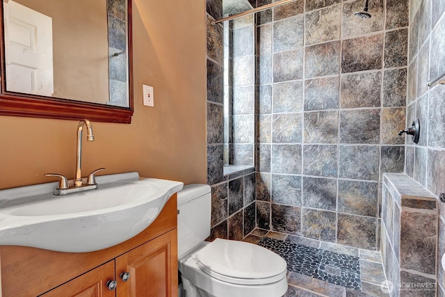 full bath featuring toilet, vanity, and a tile shower