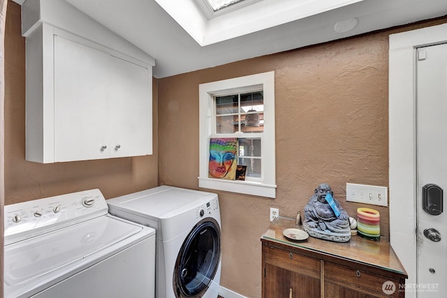 laundry area featuring cabinet space, independent washer and dryer, a skylight, and a textured wall