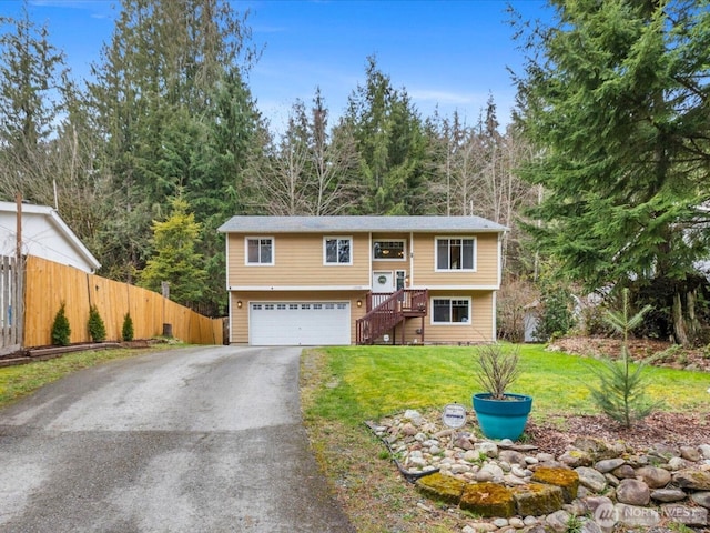 bi-level home with aphalt driveway, a garage, a front lawn, and fence