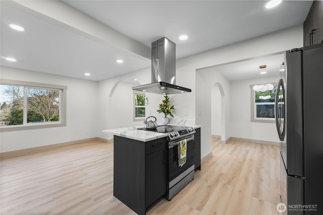 kitchen featuring island range hood, arched walkways, light wood-style flooring, appliances with stainless steel finishes, and dark cabinetry