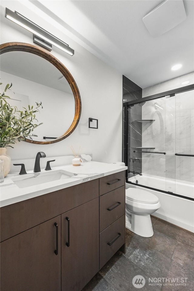 bathroom with stone finish flooring, combined bath / shower with glass door, vanity, and toilet