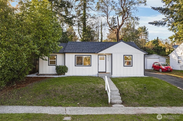 modern farmhouse style home featuring board and batten siding, an outbuilding, a front lawn, and aphalt driveway