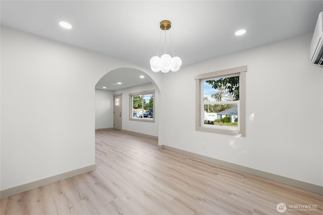 unfurnished room with light wood-style flooring, arched walkways, baseboards, and recessed lighting