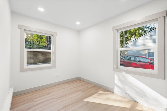 spare room with recessed lighting, wood finished floors, a wealth of natural light, and baseboards