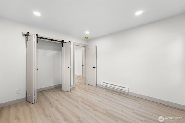 unfurnished bedroom featuring recessed lighting, a baseboard radiator, light wood-style flooring, and a barn door