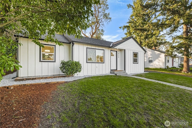 view of front of house with board and batten siding, a front yard, and a shingled roof