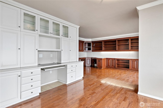 unfurnished office with crown molding, light wood-style floors, and built in study area