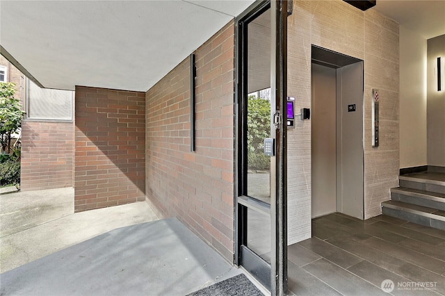 entrance to property with elevator and brick siding