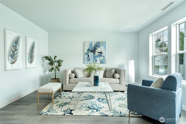 living area featuring visible vents, baseboards, and wood finished floors