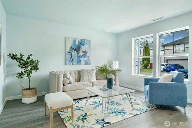 living area with wood finished floors, visible vents, and baseboards