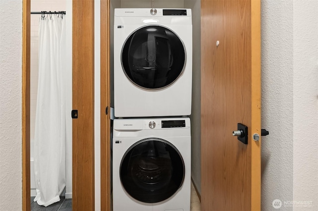 laundry room featuring laundry area, a textured wall, and stacked washer and clothes dryer