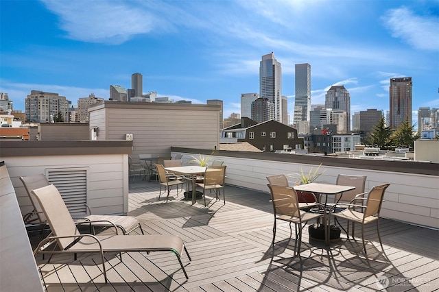 wooden terrace with a city view and outdoor dining space