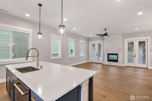 kitchen featuring french doors, light wood finished floors, recessed lighting, hanging light fixtures, and a sink