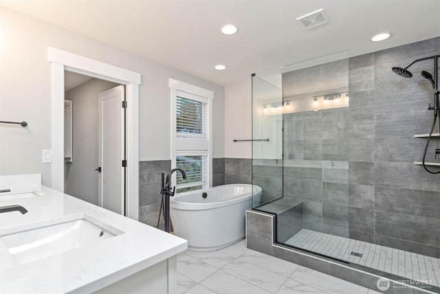 full bath featuring a tile shower, marble finish floor, a sink, and visible vents