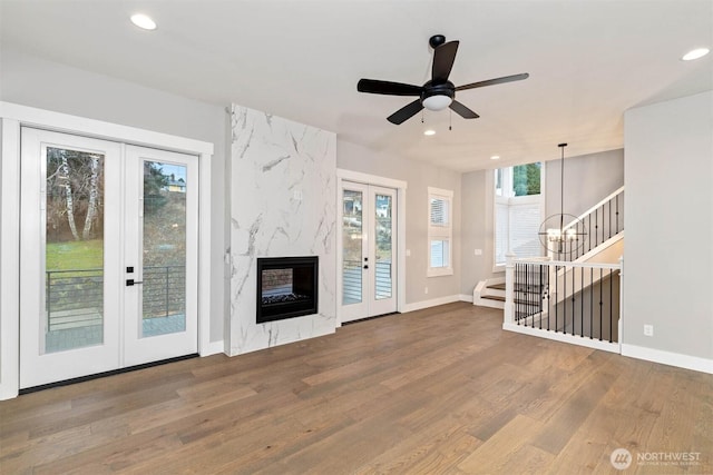 unfurnished living room with recessed lighting, stairs, wood finished floors, and french doors