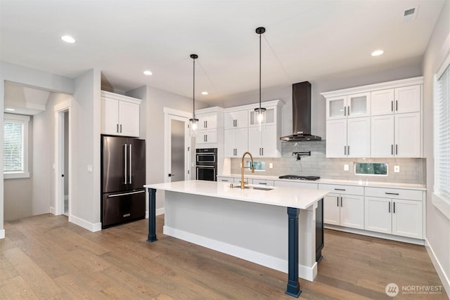 kitchen with wall chimney exhaust hood, high quality fridge, double wall oven, gas stovetop, and a sink