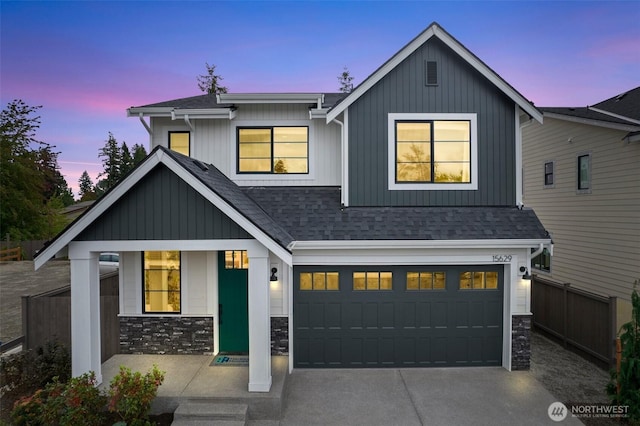 modern inspired farmhouse with a garage, stone siding, roof with shingles, and concrete driveway