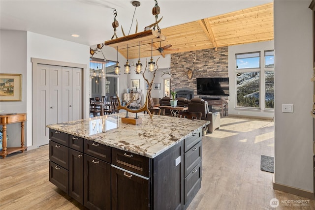 kitchen featuring light wood finished floors, a stone fireplace, wood ceiling, and lofted ceiling with beams