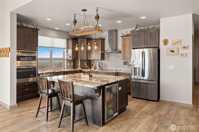 kitchen featuring backsplash, wall chimney range hood, beverage cooler, light wood-style floors, and stainless steel appliances