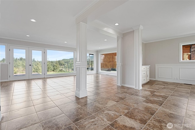 spare room featuring french doors, crown molding, recessed lighting, a decorative wall, and ornate columns