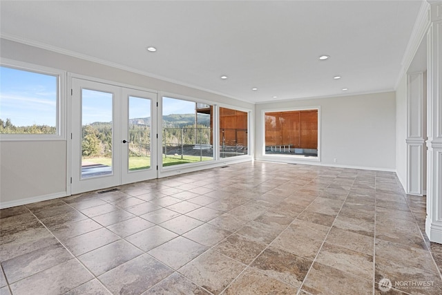 spare room featuring plenty of natural light, visible vents, ornamental molding, and baseboards