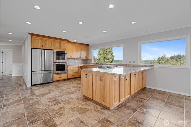 kitchen featuring decorative backsplash, a peninsula, stainless steel appliances, crown molding, and a sink