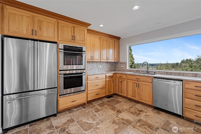 kitchen featuring stainless steel appliances, recessed lighting, backsplash, stone finish floor, and a sink