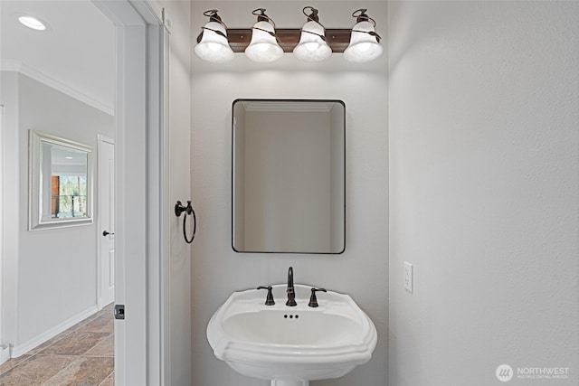 bathroom featuring baseboards, ornamental molding, a sink, and recessed lighting